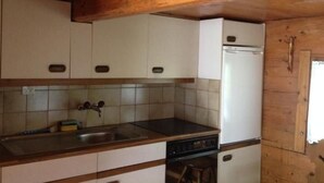 Una cocina con armarios de madera, un fregadero, una estufa y un refrigerador.