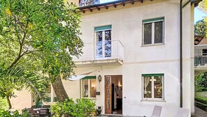 A two-story building with a balcony, stone-paved courtyard, and outdoor seating.