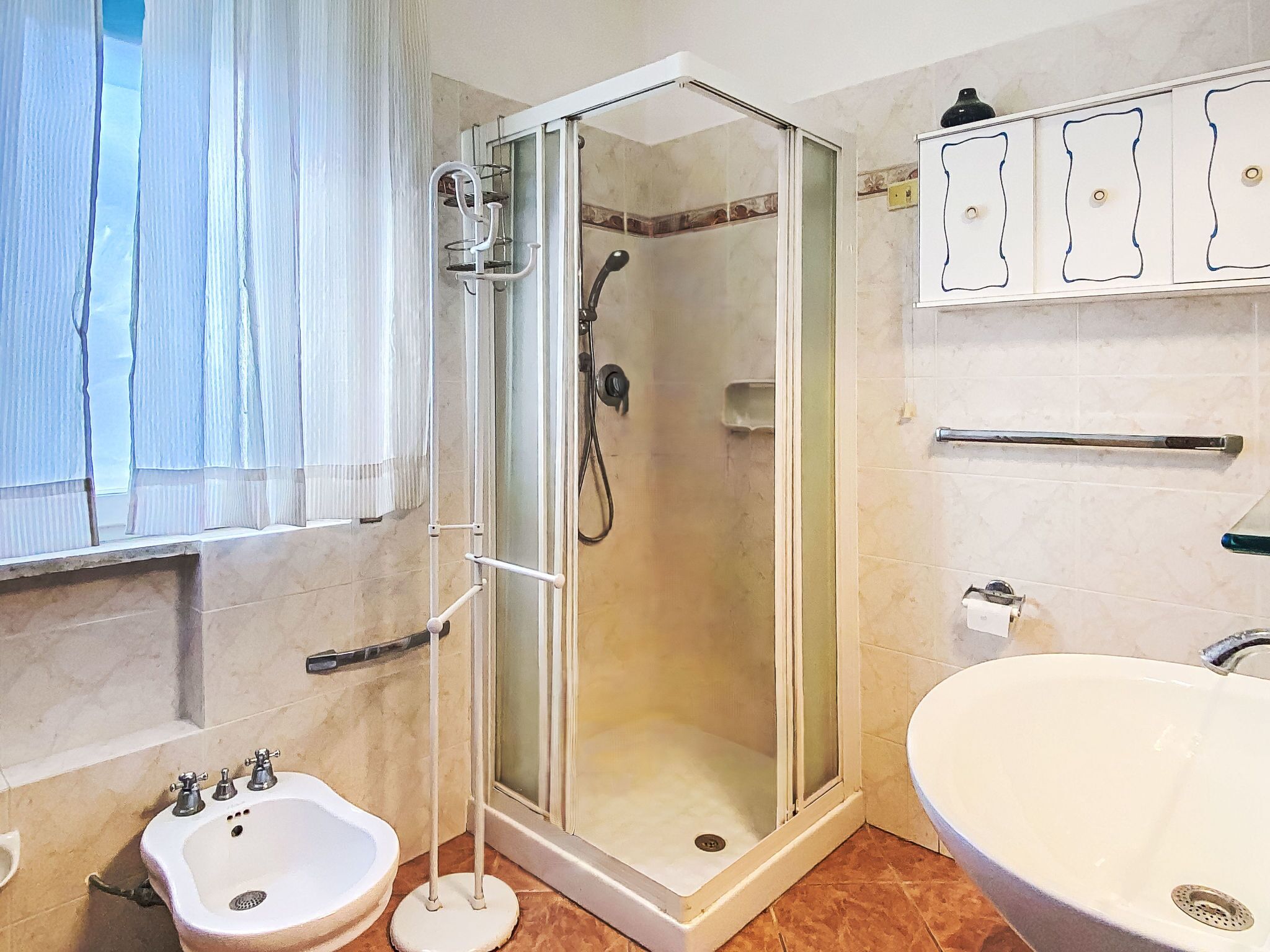 A bathroom with a glass-enclosed shower, a pedestal sink, and a freestanding bathtub.