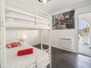 A bunk bed room with a poster of a red double-decker bus, a radiator, and a view of the outside.
