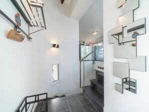 A modern interior with a staircase, wall-mounted mirrors, and a small window.