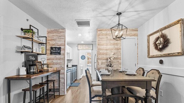 A modern kitchen with wooden shelves, a coffee station, and a dining area with a wooden table and chairs. - Ashley's Charming Chalet (Branson)