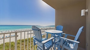 Ein Balkon mit Blick auf den Strand, blaue Stühle und ein Tisch.