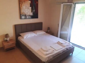 Une chambre à coucher avec un lit, une table de chevet, une lampe, un tableau et une porte-fenêtre coulissante.