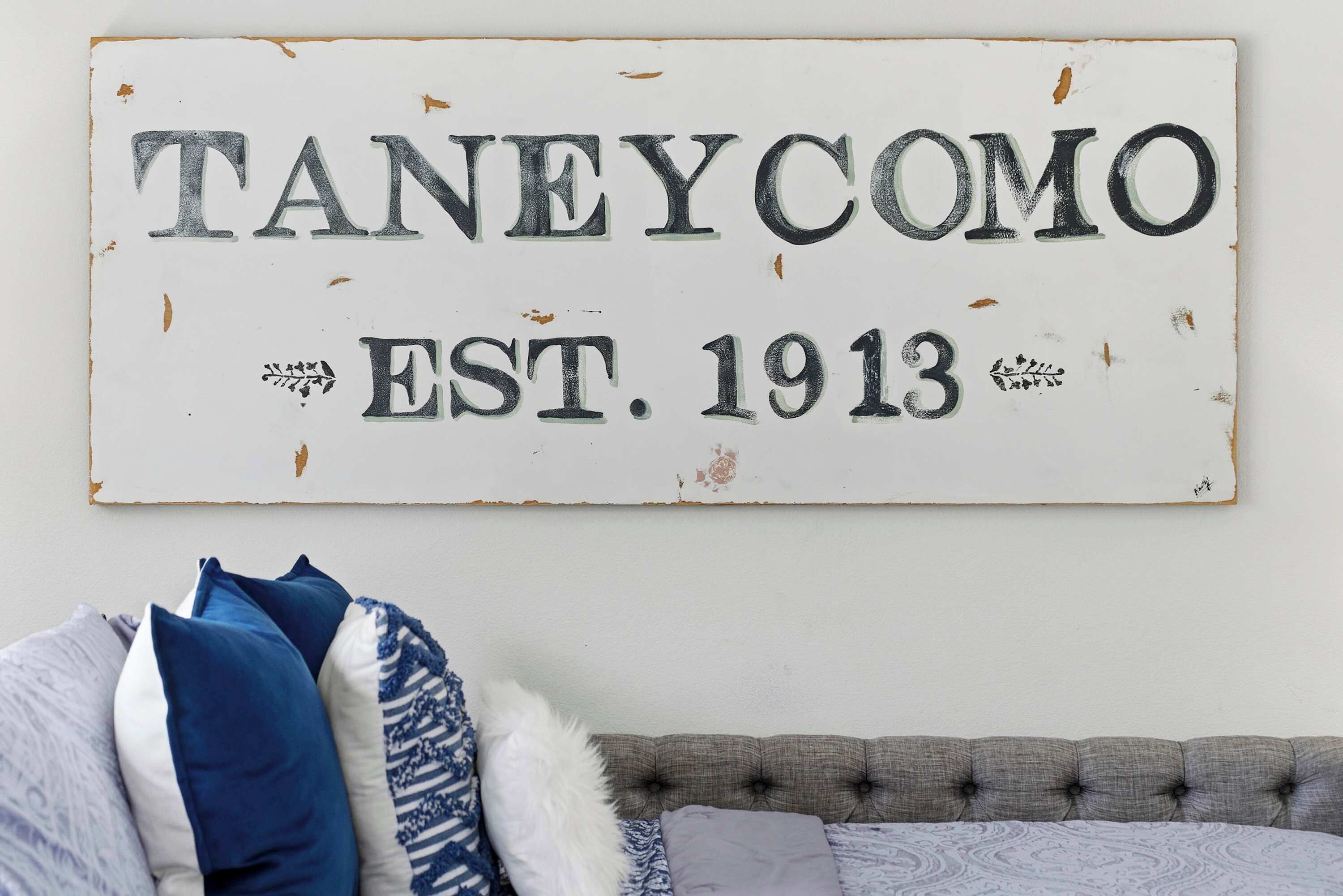 Un cartel con la inscripción "TANEYCOMO EST. 1913" sujeto a una pared.