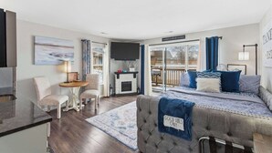 A modern living room with a fireplace, comfortable seating, and a large window with curtains. - Taneycomo Topia Quaint Studio (Branson)