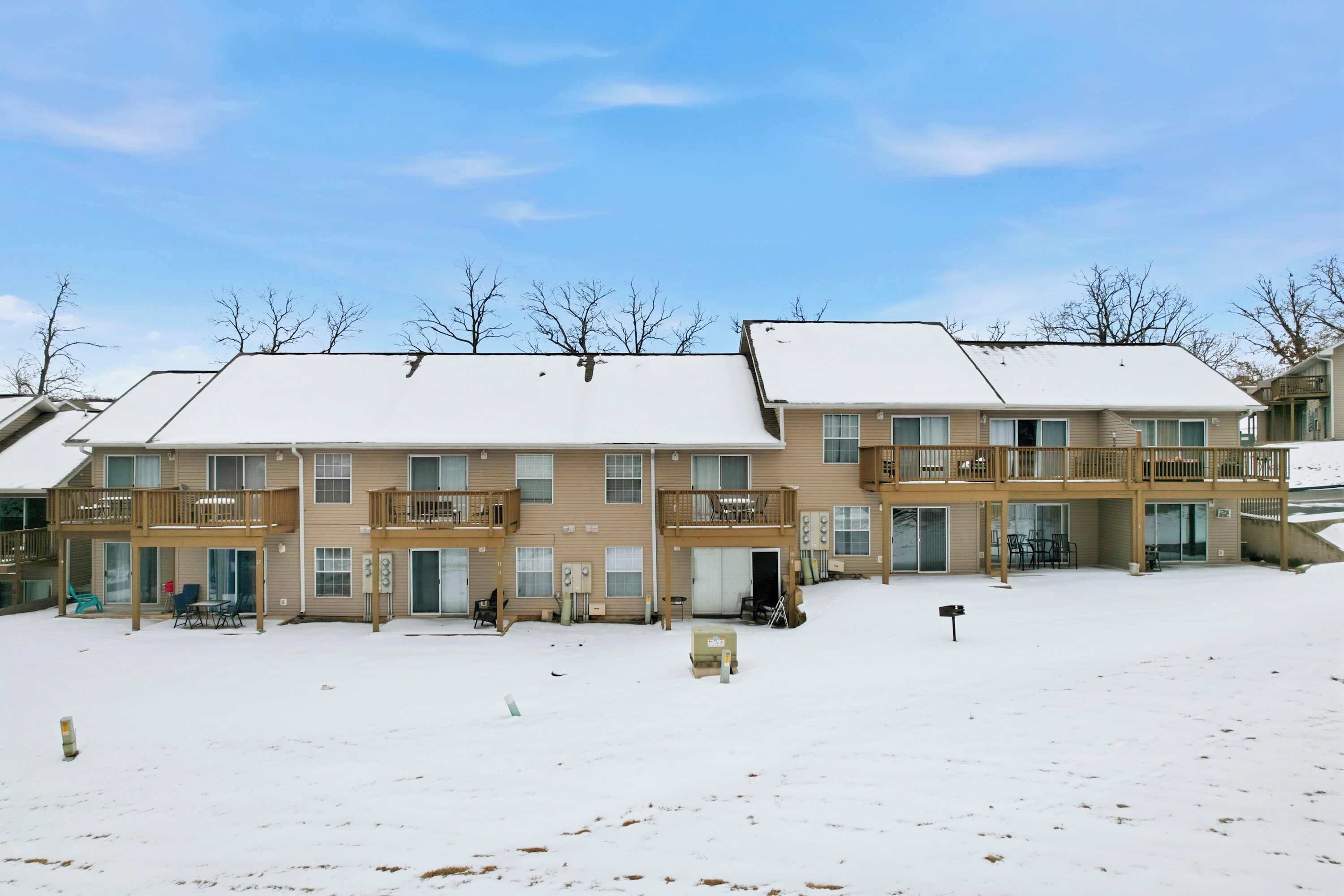 A multi-story residential building with a covered patio area and a snow-covered ground.