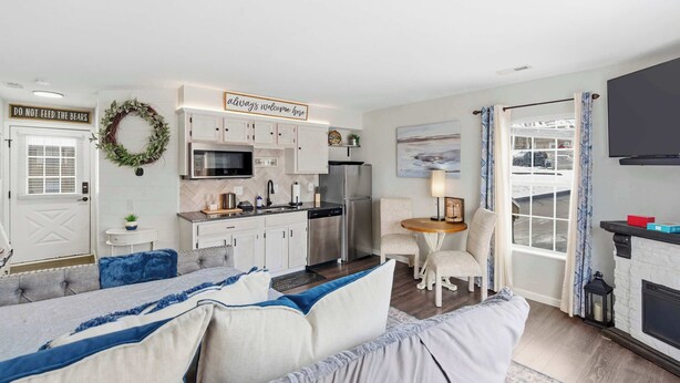 A compact living space with a kitchenette, a dining area, a sofa, and a fireplace. - Taneycomo Topia Quaint Studio (Branson)