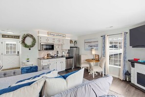 A compact living space with a kitchenette, a dining area, a sofa, and a fireplace. - Taneycomo Topia Quaint Studio (Branson)