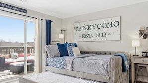 A bedroom with a large bed, a view of the outside, a sign on the wall, and a small table with a lamp. - Taneycomo Topia Quaint Studio (Branson)