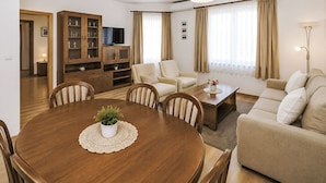 Una sala de estar moderna con una mesa de comedor, sofás, un televisor y un mueble de almacenamiento.