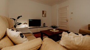 Ett vardagsrum med en soffa, en tv, ett soffbord och en dörr.