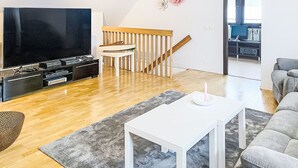 A modern living room with a flat-screen TV, wooden flooring, a white coffee table, and a grey sofa. - Villa Daniel by Interhome (Storebro)