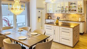 A modern kitchen with white cabinetry, a central island, and a dining area with a chandelier. - Villa Daniel by Interhome (Storebro)