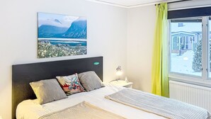 A neatly made bed with a headboard, a bedside lamp, and a painting of a mountainous landscape. - Villa Daniel by Interhome (Storebro)