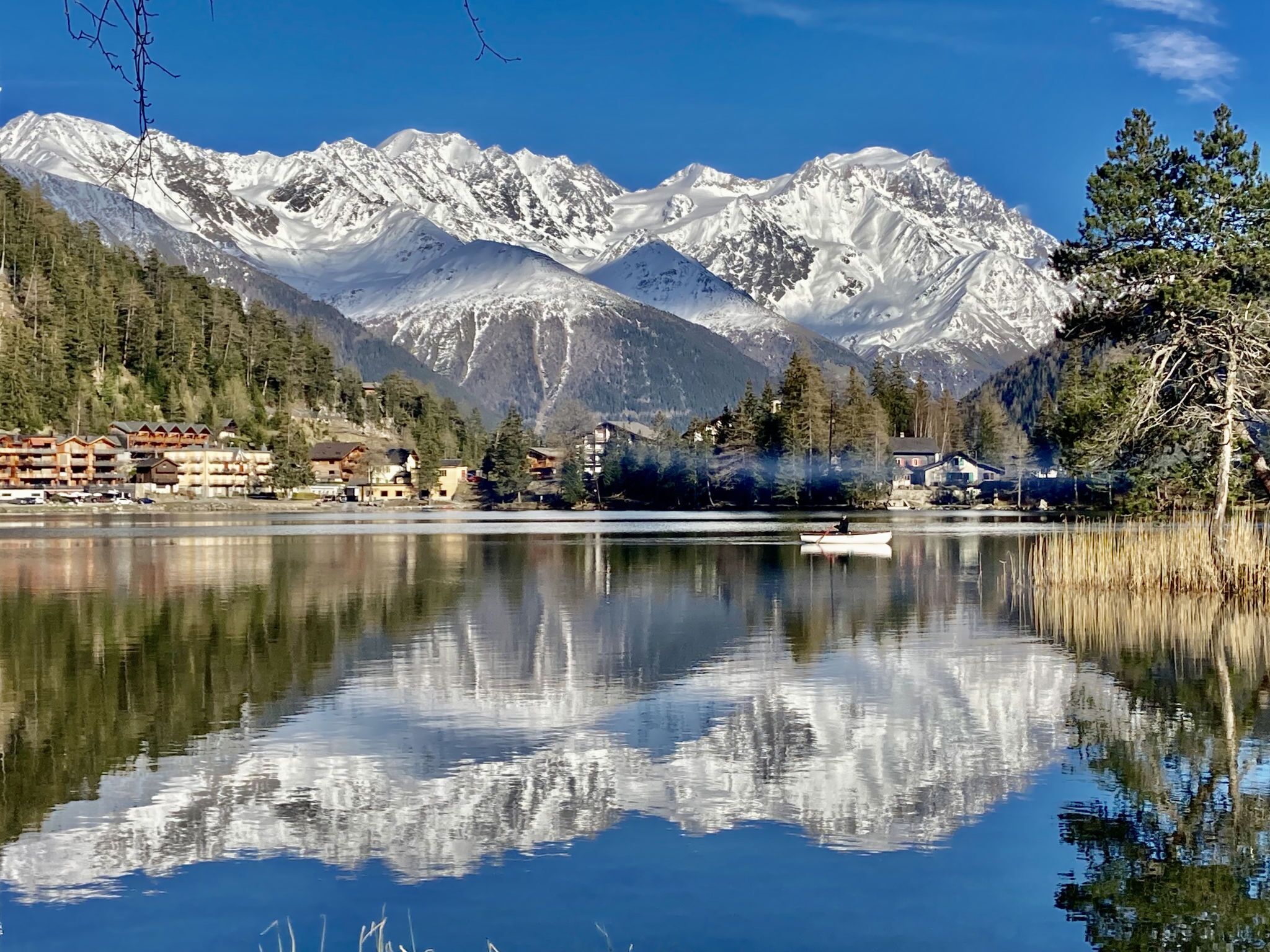 A mountain lodge with a lake in front, reflecting the mountains.