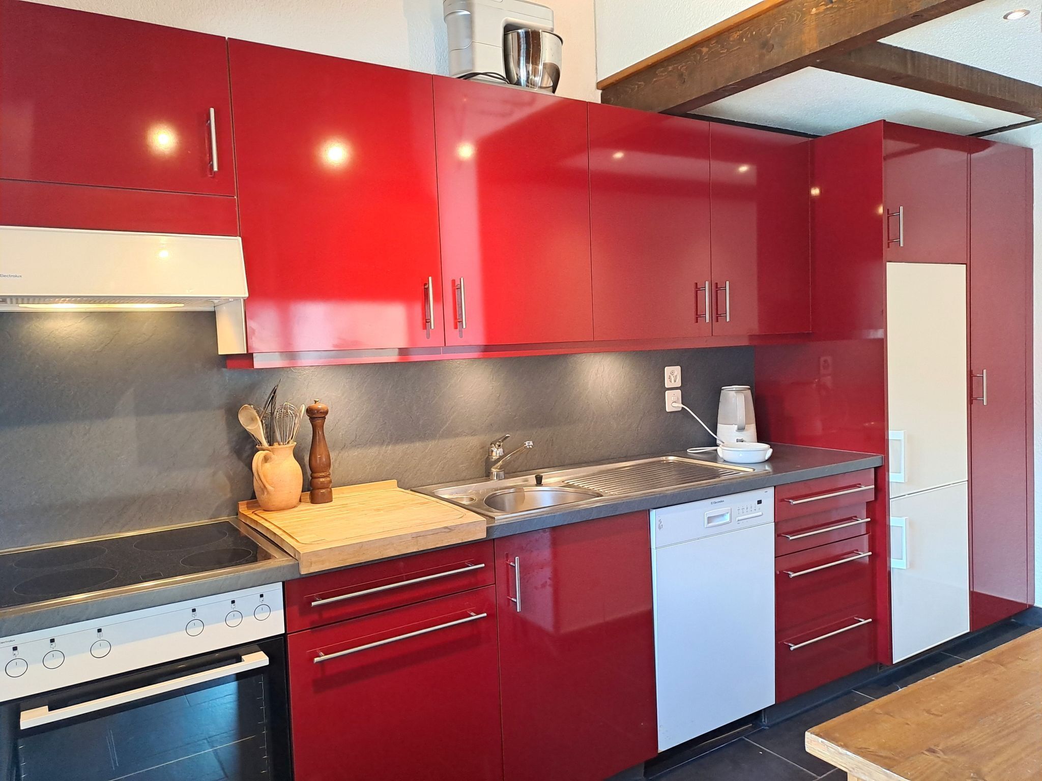 Una cocina moderna con armarios rojos, electrodomésticos de acero inoxidable y encimera de madera.