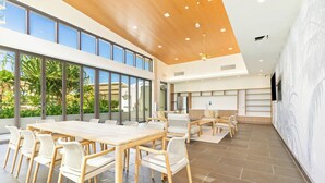 A spacious indoor area with a large wooden table and chairs, large windows, and a modern ceiling design. - Chic Studio with Skyline Views at The Park on Keeaumoku (Honolulu)