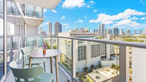 A balcony with a table and chairs, offering a city view. - Chic Studio with Skyline Views at The Park on Keeaumoku (Honolulu)