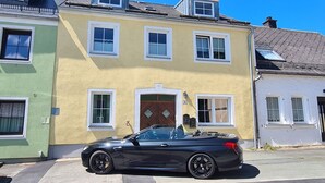 A two-story building with a green and yellow facade, a black convertible parked in front, and a clear blue sky. - Kraxler Single by Interhome (Weißenstadt)