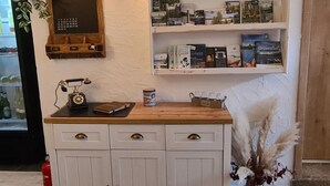 A reception area with a wooden counter, a vintage telephone, a calendar, and shelves with books and magazines. - Kraxler Single by Interhome (Weißenstadt)