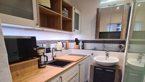 A modern kitchen with white cabinets, a wooden countertop, a built-in microwave, a coffee maker, and a sink. - Kraxler Single by Interhome (Weißenstadt)