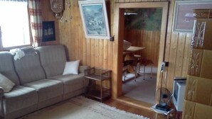 Ein Wohnzimmer mit einer Couch, einem kleinen Tisch, einem Fernseher und einer Holztür, die in einen anderen Raum führt.