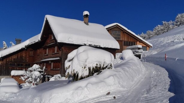 Eine Holzhütte mit schneebedecktem Dach und blauem Himmel.