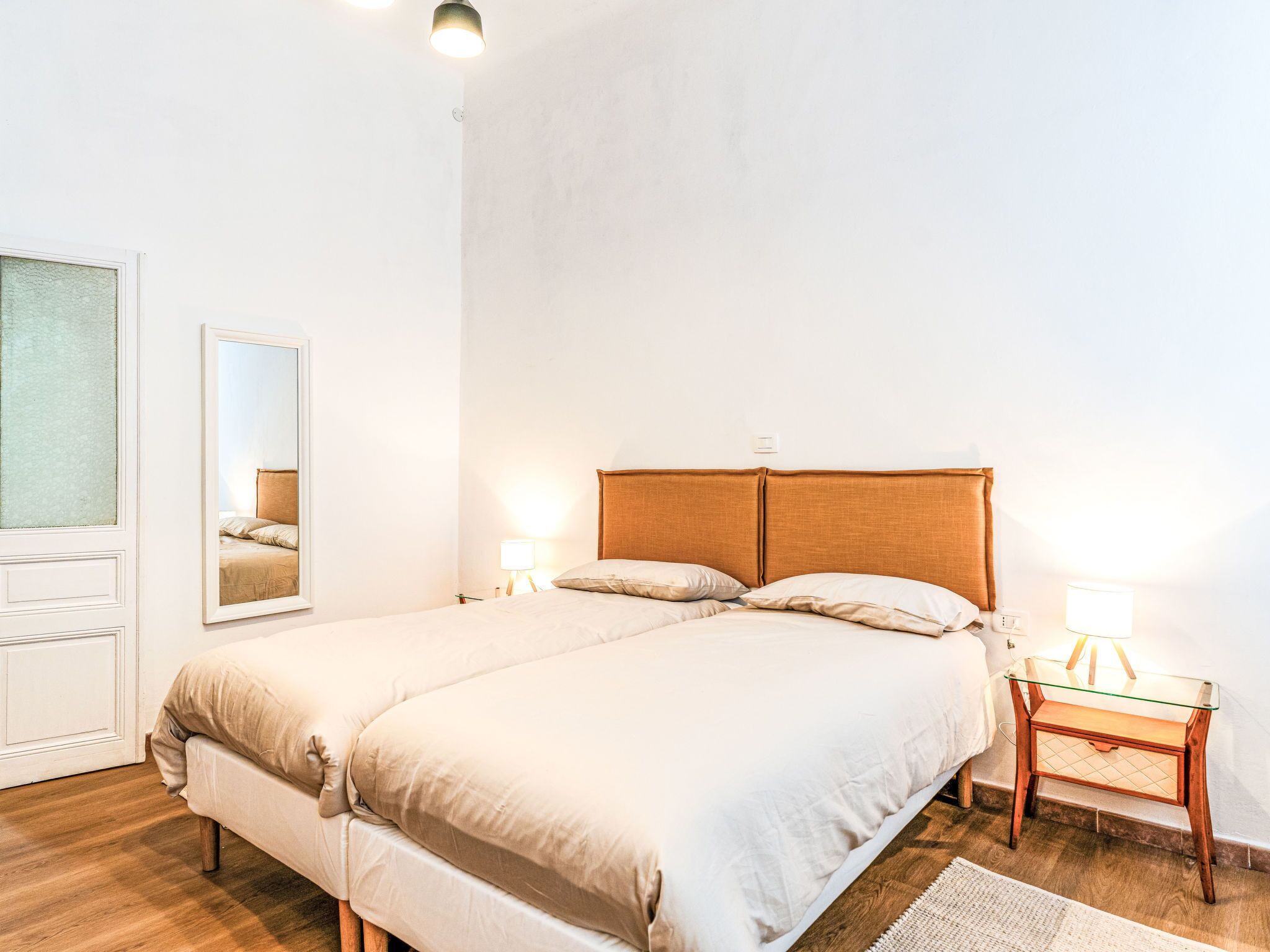 Une chambre à coucher avec un lit, des lampes de chevet, un miroir et une table de chevet en bois.