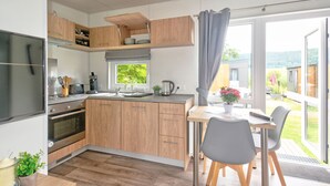 Eine moderne Küche mit Holzausstattung, einem eingebauten Backofen und einem Fenster mit Blick auf einen Garten.