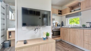 Eine moderne Küche mit Holzausstattung, einem Backofen, einer Kaffeemaschine und einem Fenster mit Blick auf Grünflächen.