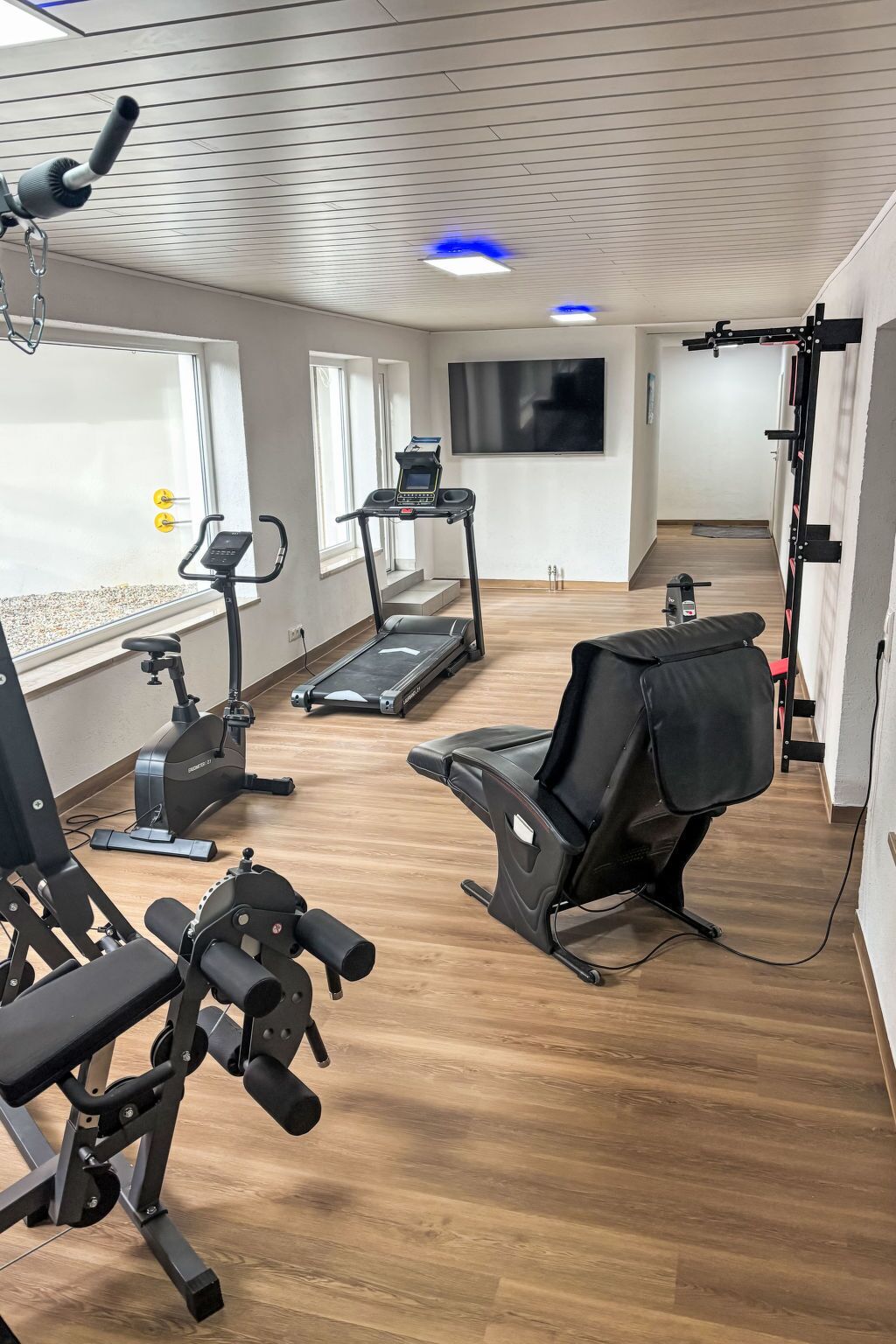 Une salle de sport à domicile équipée d’un tapis de course, d’un vélo d’appartement et d’un banc de musculation.