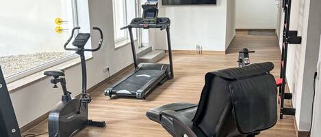 Une salle de sport à domicile équipée d’un tapis de course, d’un vélo d’appartement et d’un banc de musculation.