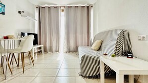 Ein modernes Wohnzimmer mit einem gestreiften Sofa, einem weißen Tisch, einem Fernseher und einem Essbereich mit Stühlen.