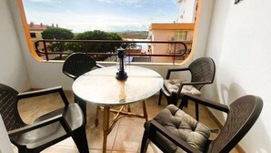 Ein Balkon mit Glastisch, zwei Stühlen und einer Laterne.