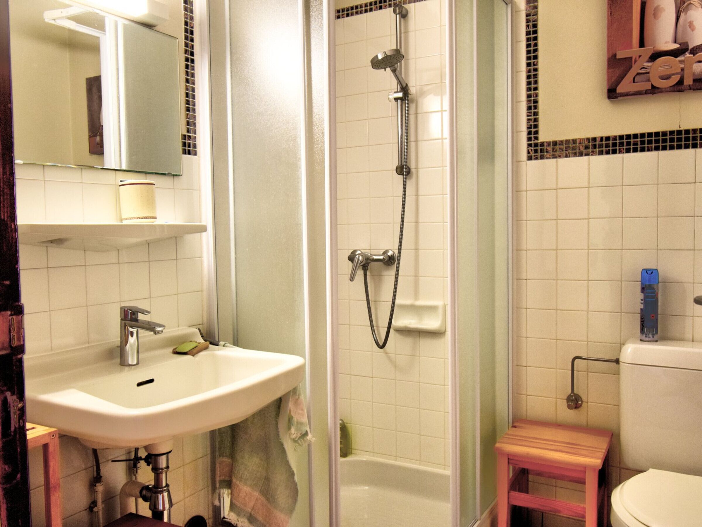 A bathroom with a sink, mirror, shower, and toilet.