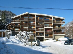 A multi-story hotel with balconies, surrounded by snow-covered trees and mountains. - Lovely apartment in Morzine with parking near the center (Morzine)