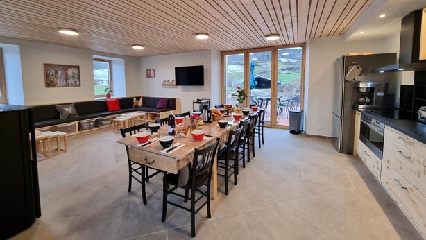 Une cuisine moderne avec un coin repas, de grandes fenêtres et une vue sur l’extérieur.