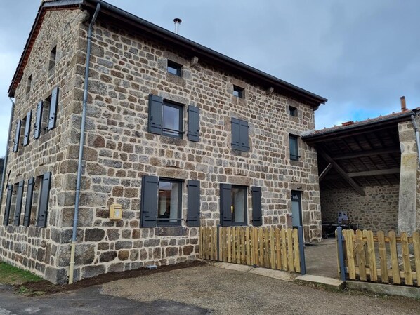 Un edificio de piedra con varias ventanas y una valla de madera.