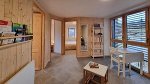 Une pièce confortable aux murs en bois, avec un lit, un bureau et une fenêtre équipée de stores.
