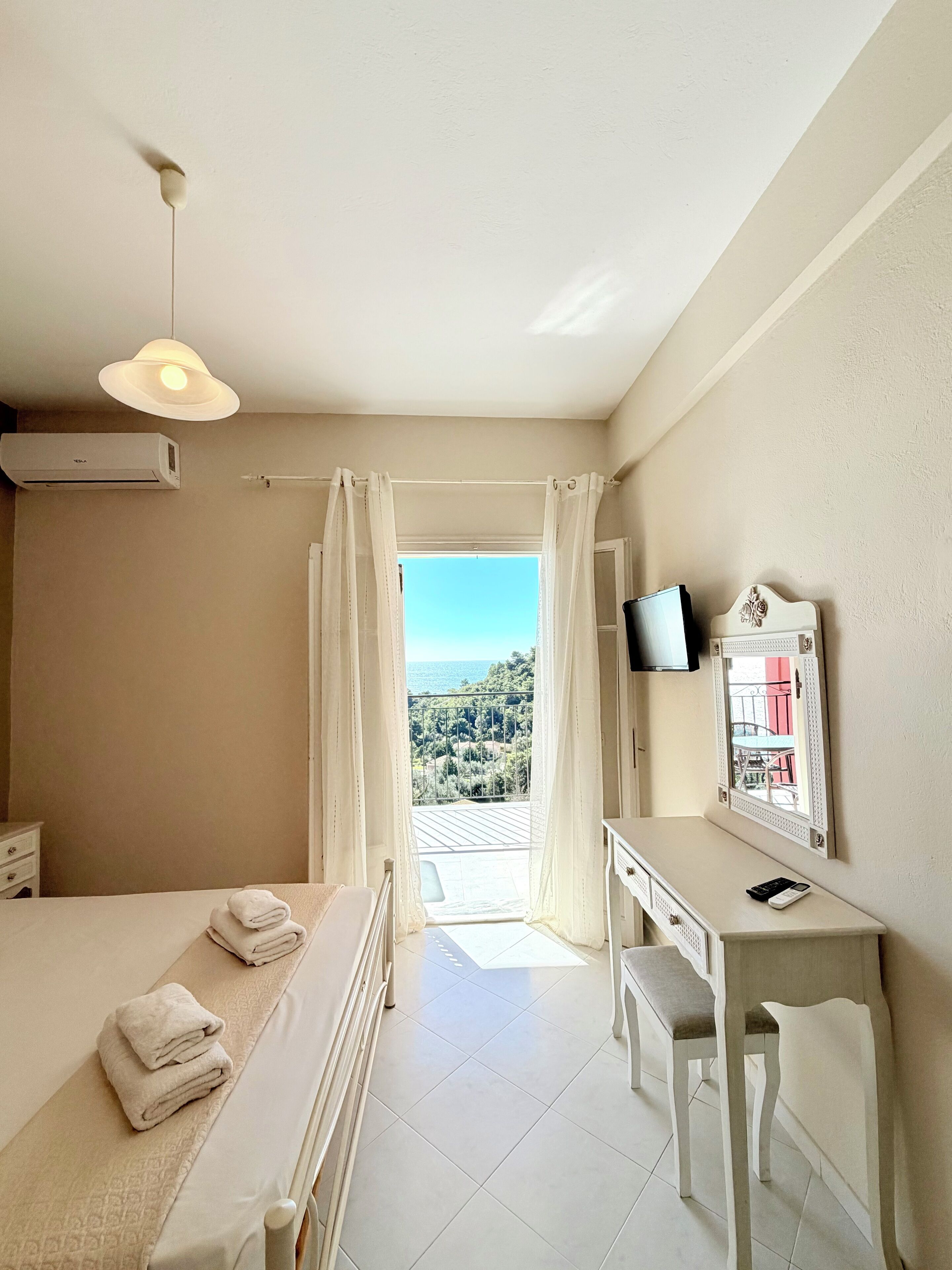Una camera d'albergo con un letto, una scrivania, una televisione e vista sul mare.