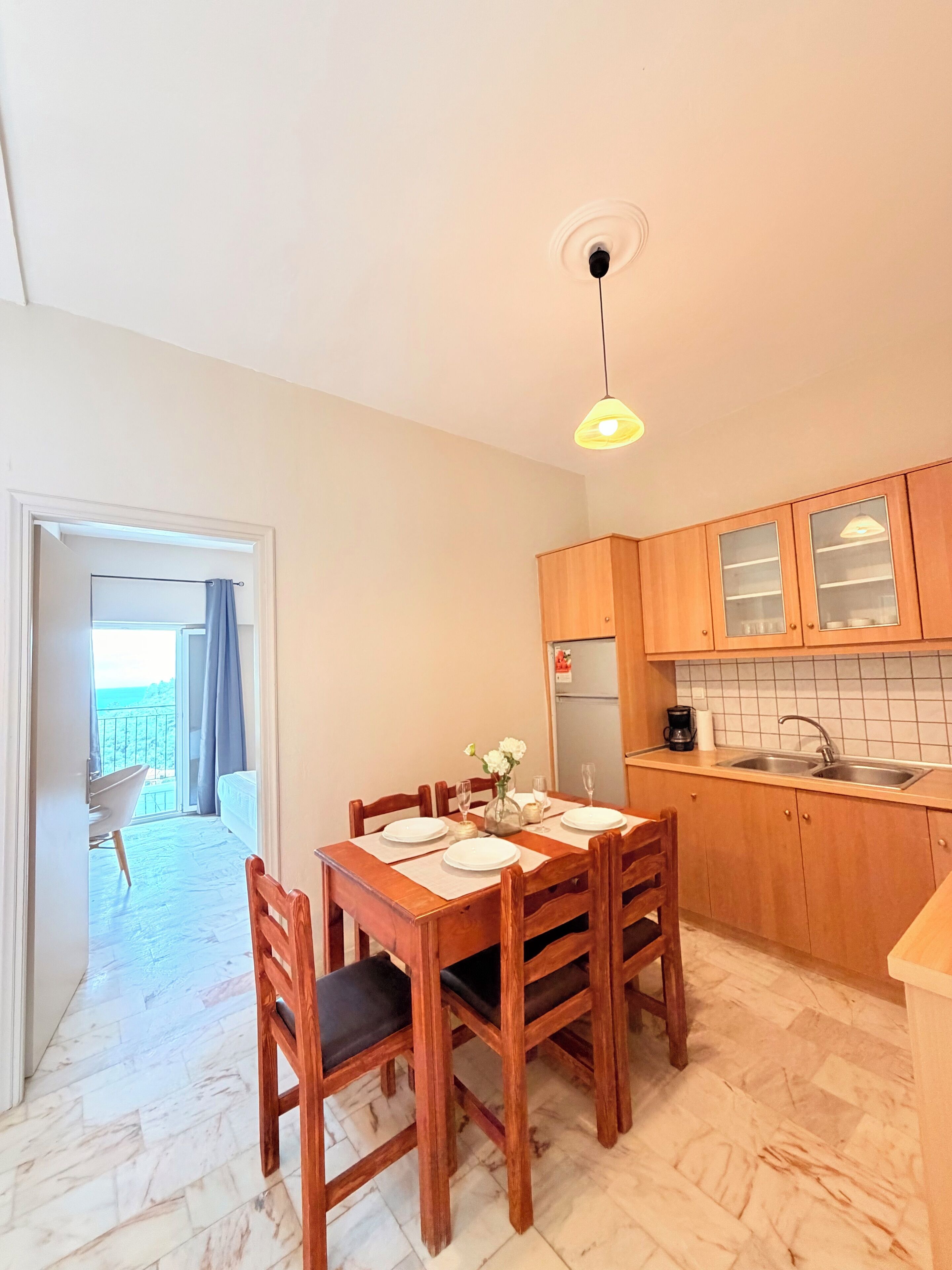 A compact kitchen with wooden cabinets and a dining area with a table set for four.