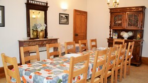 Ein Essbereich mit einem langen Holztisch, sechs Stühlen, einer Kandelaber und einem Holzschrank, sowie einem Spiegel an der Wand.
