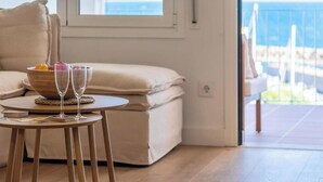 Una habitación acogedora con una mesa de madera, dos vasos, un bol con frutas y un sofá con cojines.