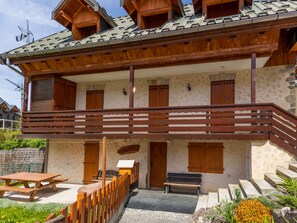 Ein zweistöckiges Holzhaus mit einem Balkon, einem Picknicktisch und einer Bank.