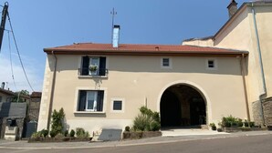 A two-story building with a red-tiled roof, a central archway, and a small balcony with a flower pot. - Spacious Gîte in Selles, 3 Bedrooms, Garden, Family-Friendly (Selles)
