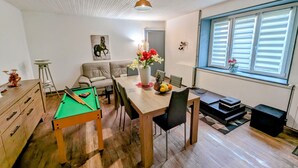 A cozy living room with a pool table, a dining table with chairs, a sofa, and a window with blinds. - Spacious Gîte in Selles, 3 Bedrooms, Garden, Family-Friendly (Selles)