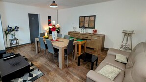 A modern living room with a wooden dining table, grey chairs, a beige sofa, and a small black coffee table. - Spacious Gîte in Selles, 3 Bedrooms, Garden, Family-Friendly (Selles)