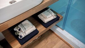 Ein Badezimmer mit einem hölzernen Waschtisch, einer weißen Spüle und zwei Handtüchern auf einem Regal.
