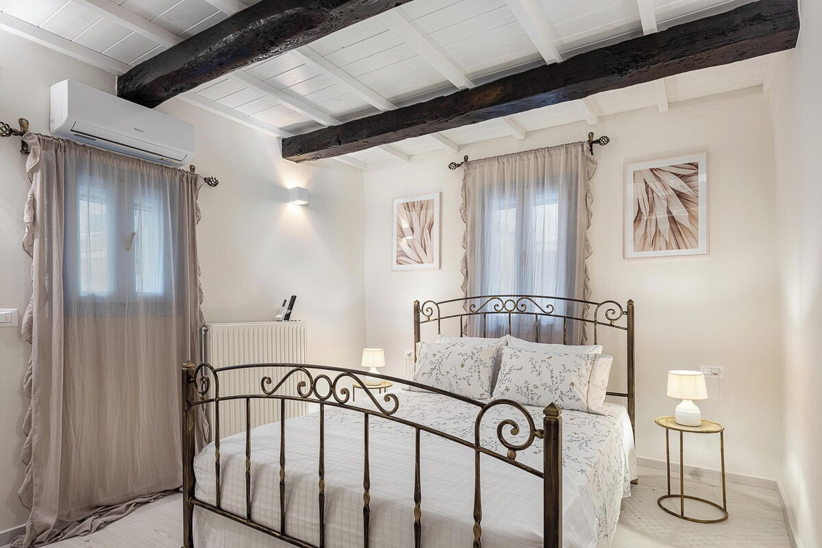 A bedroom with a bed, bedside lamps, a radiator, and artwork on the walls.